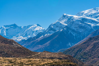 Scenic view of snowcapped mountains against clear blue sky