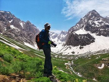 Man standing on snowcapped mountain against sky