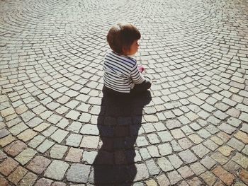 High angle view of toddler girl sitting on cobbled street