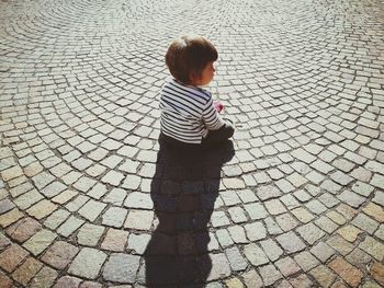 Shadow of boy standing on cobblestone