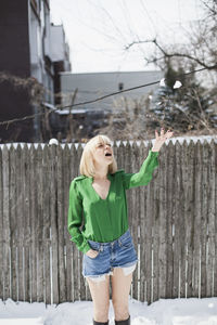 Full length of woman standing by fence