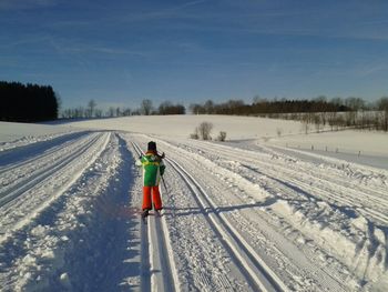 Rear view of man on snow covered field against sky