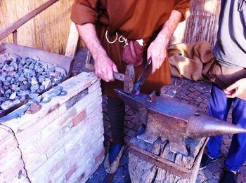 Low section of blacksmith hammering horseshoe on anvil