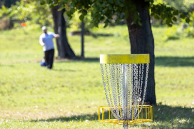 Playing flying disc golf sport game in the nature, target basket in focus
