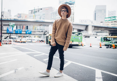 Full length portrait of young woman standing in city