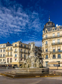 Statue of fountain in city against sky