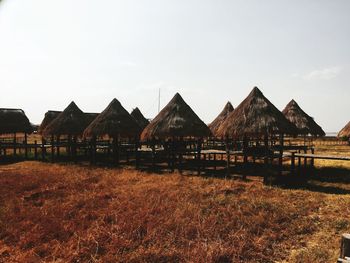 Built structure on field by houses against sky