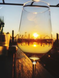 Close-up of wine glass on table against sky during sunset