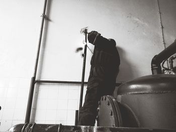 Low angle view of man working on wall