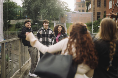 Male and female teenage friends having fun on footpath