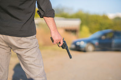 Midsection of man holding gun outdoors