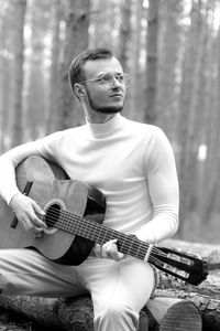 Man playing guitar in forest 