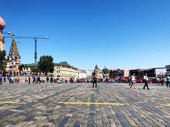 People on street against clear blue sky