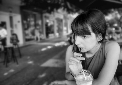 Thoughtful woman drinking milkshake at sidewalk cafe