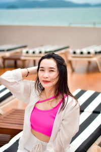 Portrait of young woman sitting on railing