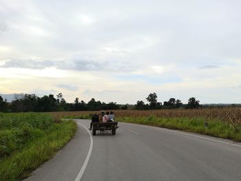 People riding motorcycle on road against sky