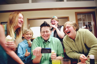 Happy family looking in smart phone while enjoying at restaurant