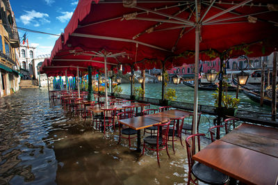 Chairs and tables in restaurant by buildings in city