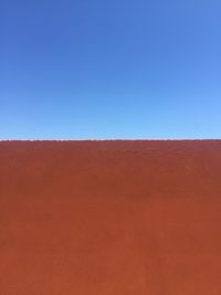 Low angle view of desert against clear blue sky