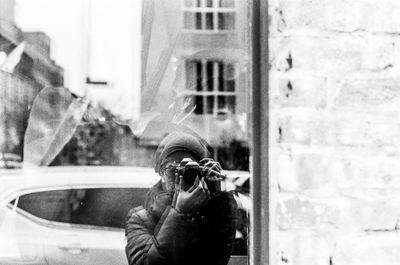 Woman photographing while standing in front of window display