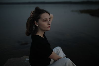 Young woman looking away while sitting in water