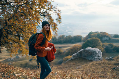 Full length of woman standing by tree during autumn