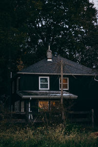 Old house on field against trees in forest