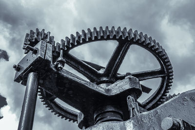 Low angle view of machine part against sky