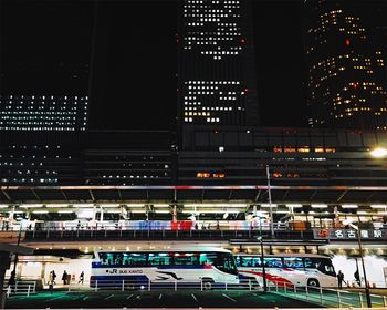 Buses outside illuminated nagoya station in city at night