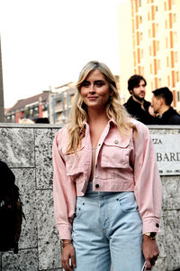 Young woman standing against wall in city