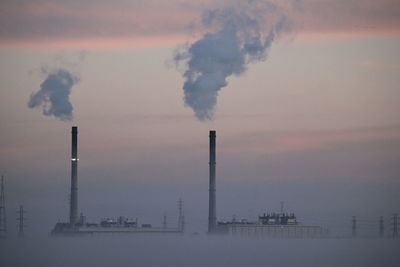 Smoke emitting from chimney against foggy sky