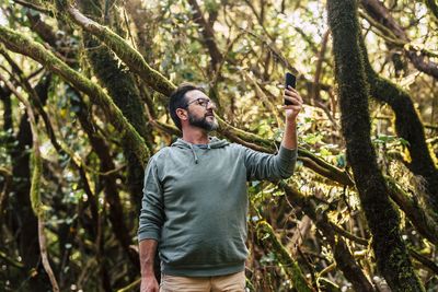 Young man using mobile phone in forest