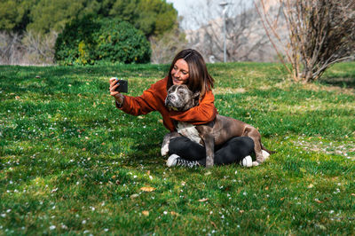 Portrait of young woman with dog on field