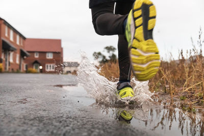 Low section of man running in water puddle during rainy season