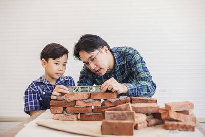 Father teaching son to make brick wall at workshop