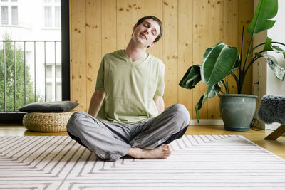 Man stretching while sitting on carpet at home