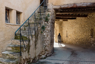 Rear view of man walking on street amidst buildings