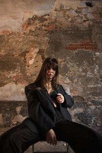 Young woman sitting against wall