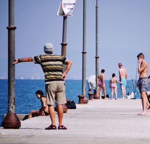 Rear view of people walking on street against clear sky