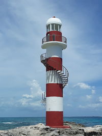 Lighthouse by sea against sky