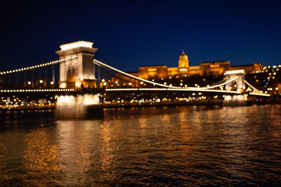 Illuminated bridge over river at night