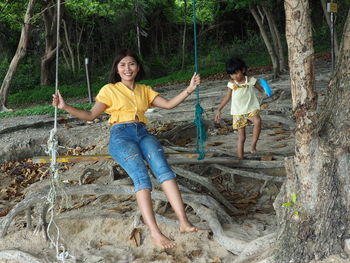 Portrait of woman sitting swing by daughter