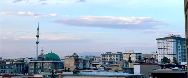 Buildings in city against cloudy sky