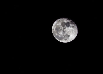 Low angle view of full moon against dark sky