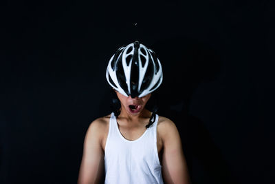 Portrait of young woman against black background