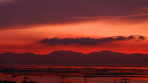 Scenic view of silhouette mountains against dramatic sky during sunrise