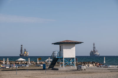 Two huge gas drilling ships at the beach of larnaka with sunshades and sunloungers in the front.