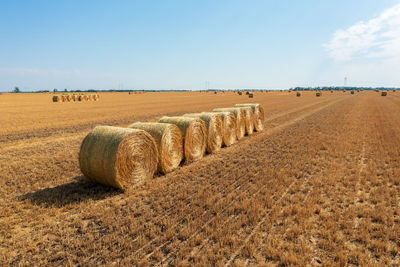 Hay bales on field against sky