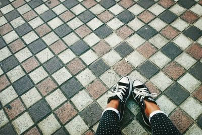 Low section of woman in shoes on tiled floor