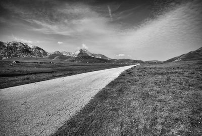 Empty road amidst landscape against sky